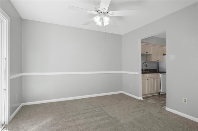 unfurnished room with a sink, baseboards, ceiling fan, and carpet flooring