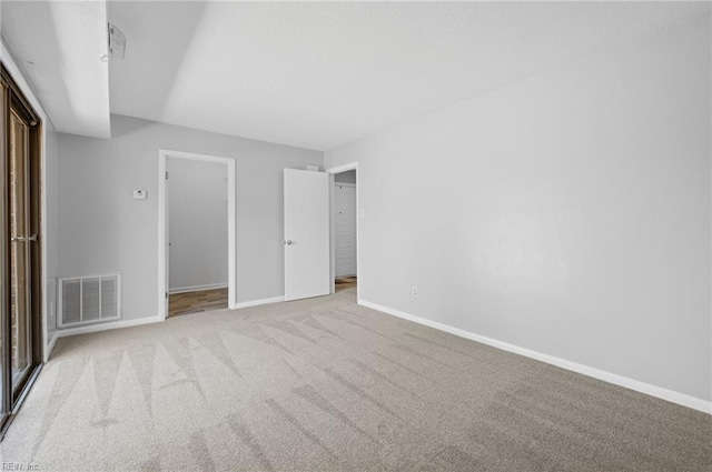 unfurnished bedroom with carpet flooring, baseboards, and visible vents