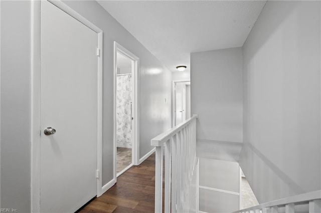 hall featuring an upstairs landing and dark wood-type flooring