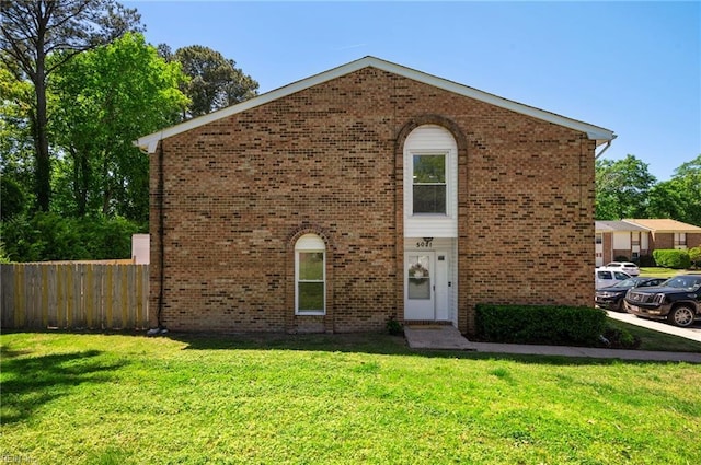 traditional home featuring fence, brick siding, and a front yard