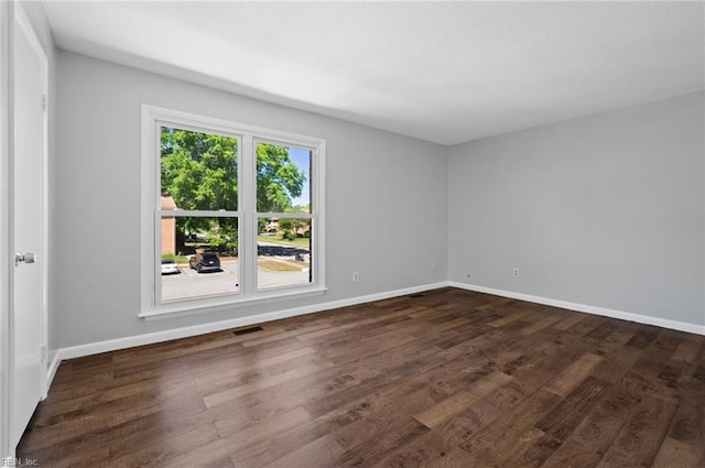 spare room with baseboards, dark wood finished floors, and visible vents