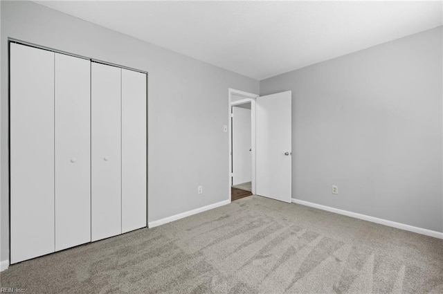 unfurnished bedroom featuring carpet floors, baseboards, and a closet