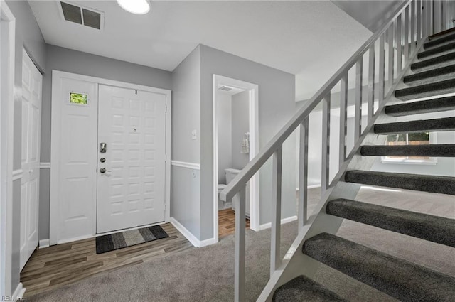 foyer entrance with baseboards, carpet flooring, stairs, and visible vents