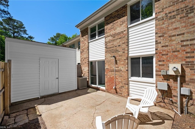 rear view of property with fence, a patio, an outbuilding, and brick siding