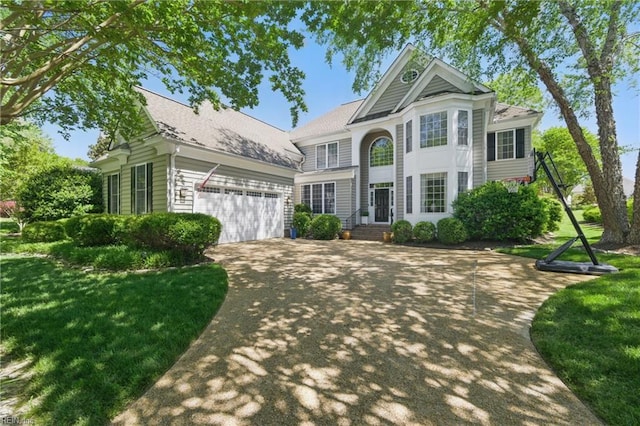 traditional-style house featuring a garage, a front lawn, and driveway