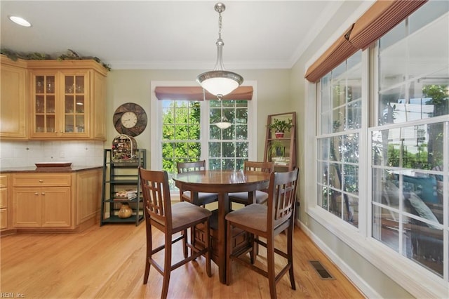 dining room with visible vents, ornamental molding, and light wood-style flooring
