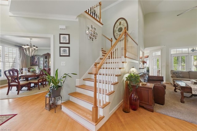 stairs featuring a notable chandelier, ornamental molding, and a healthy amount of sunlight
