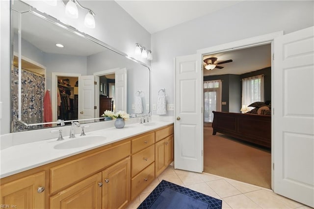 full bathroom with double vanity, a ceiling fan, a walk in closet, tile patterned floors, and a sink
