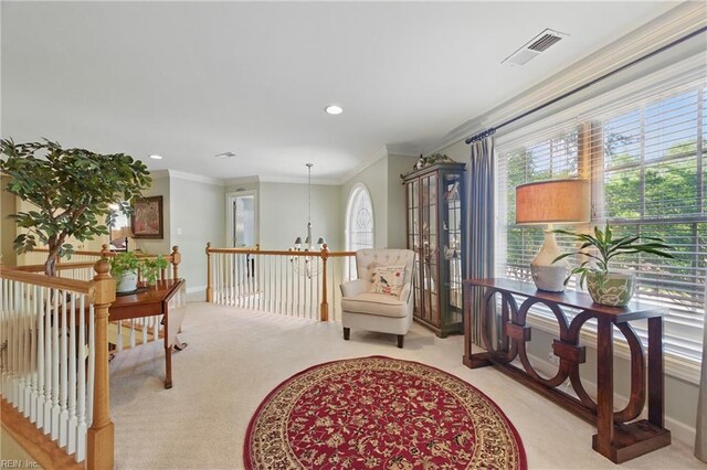 sitting room featuring light colored carpet, crown molding, visible vents, and an upstairs landing