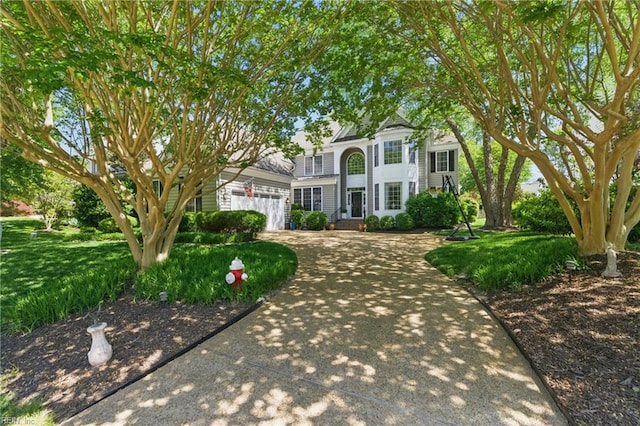 colonial home featuring concrete driveway and a front yard