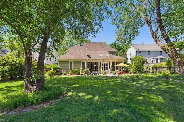 back of house featuring a lawn, fence, and a sunroom