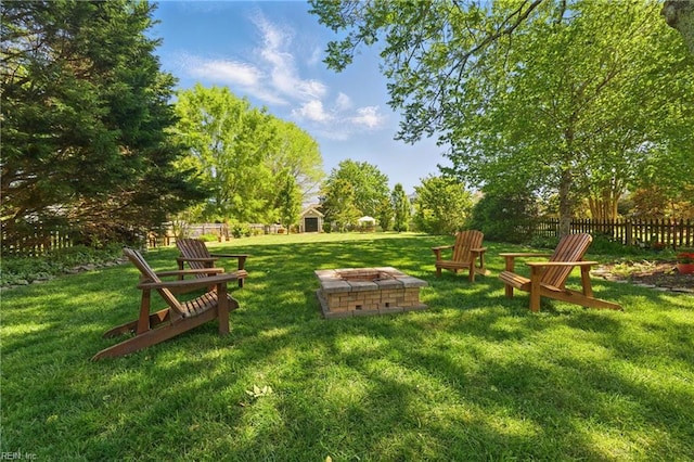 view of yard with fence, an outbuilding, a shed, and an outdoor fire pit