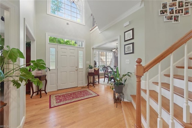 foyer entrance featuring a high ceiling, a healthy amount of sunlight, stairway, and light wood-type flooring