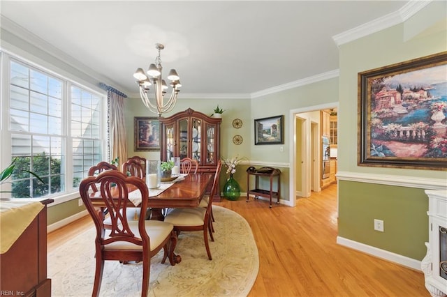 dining area featuring an inviting chandelier, light wood-style floors, crown molding, and baseboards