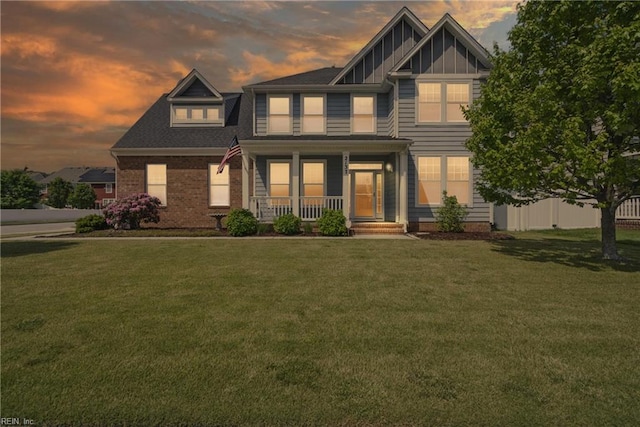 view of front of house featuring covered porch, a yard, and board and batten siding