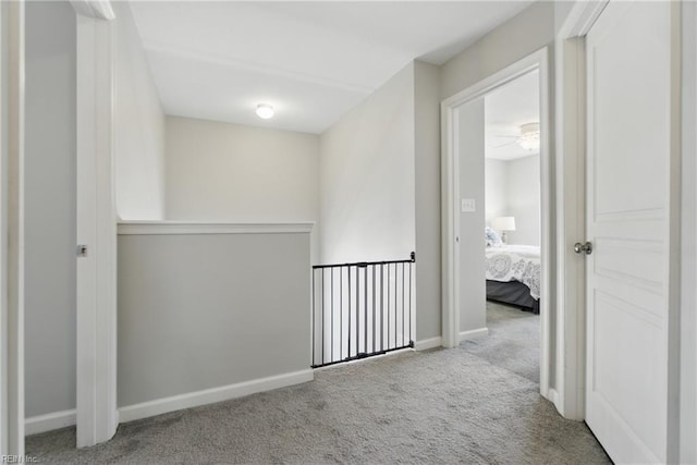 corridor featuring baseboards and carpet flooring