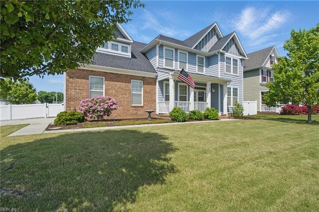 craftsman-style home with brick siding, a front lawn, fence, and covered porch