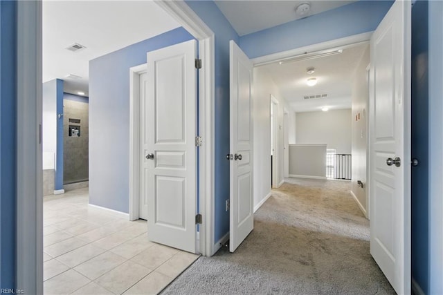 corridor with visible vents, baseboards, and light tile patterned floors