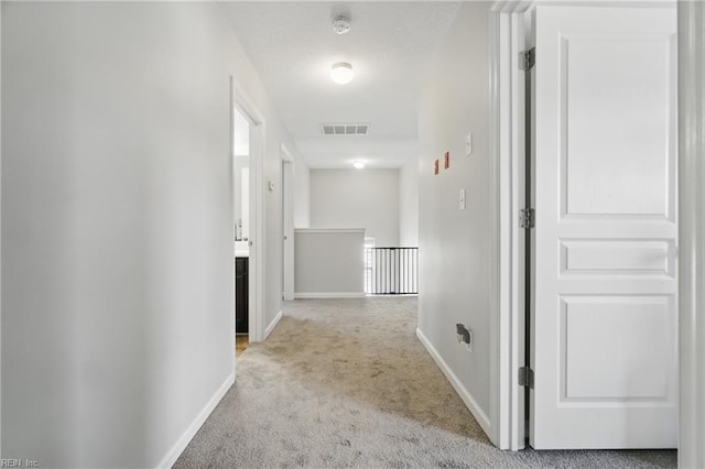 corridor featuring baseboards, light carpet, and visible vents