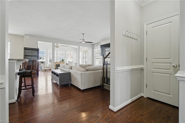 living room with baseboards, ceiling fan, and dark wood-style flooring
