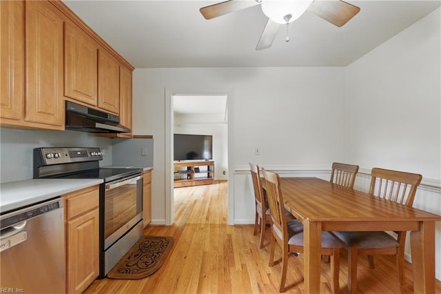 kitchen with light countertops, under cabinet range hood, a ceiling fan, light wood-style flooring, and stainless steel appliances
