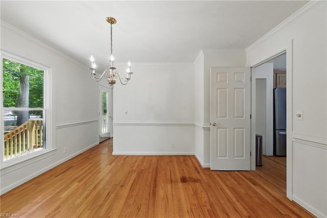 unfurnished dining area featuring crown molding, a notable chandelier, plenty of natural light, and light wood-style floors