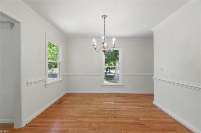 unfurnished dining area featuring visible vents, crown molding, light wood-type flooring, baseboards, and a chandelier