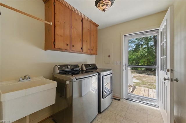 washroom with cabinet space, light tile patterned flooring, washing machine and dryer, and a sink