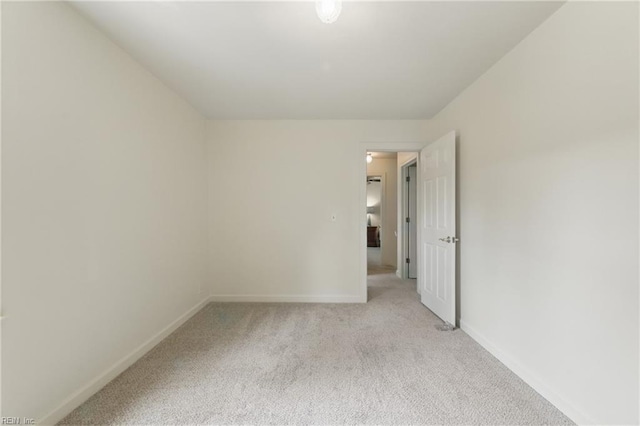 unfurnished room featuring baseboards and light carpet