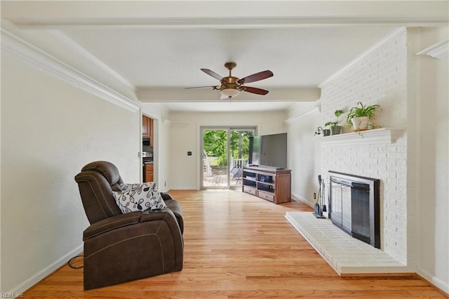living area with a ceiling fan, light wood-style flooring, a fireplace, and ornamental molding