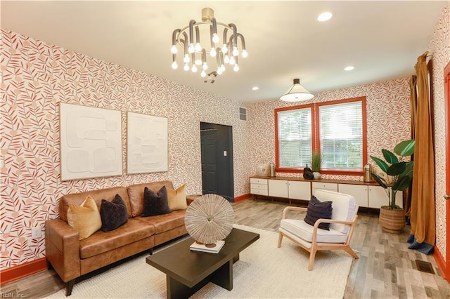 living area featuring visible vents, wood finished floors, baseboards, wallpapered walls, and a chandelier