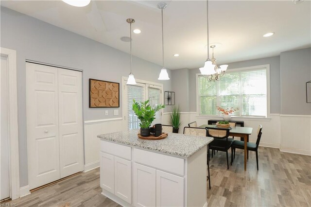 kitchen featuring light wood-type flooring, wainscoting, a notable chandelier, and a kitchen island
