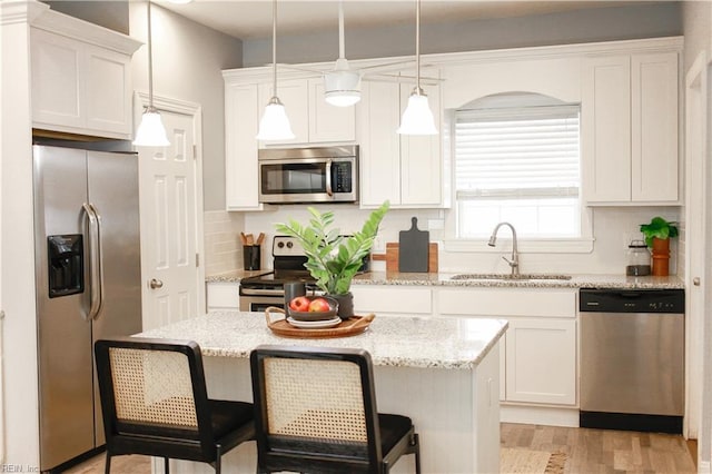 kitchen featuring a sink, tasteful backsplash, stainless steel appliances, and white cabinetry