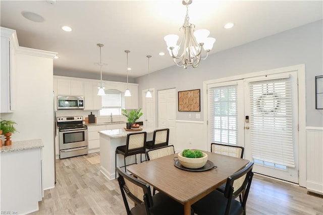 dining space featuring an inviting chandelier, wainscoting, light wood-type flooring, and visible vents