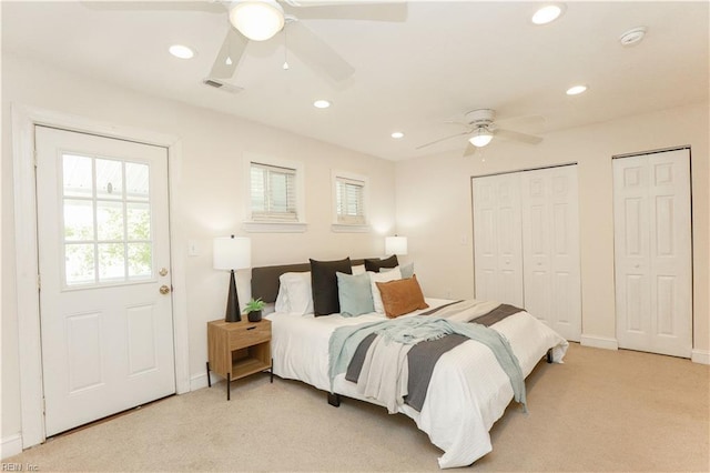 bedroom featuring baseboards, light carpet, two closets, and recessed lighting
