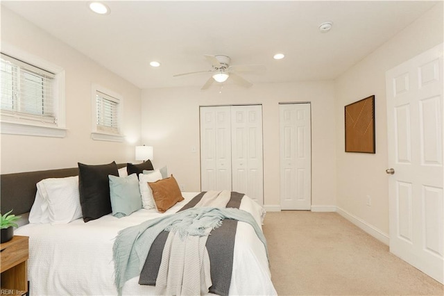 bedroom with ceiling fan, light colored carpet, baseboards, multiple closets, and recessed lighting