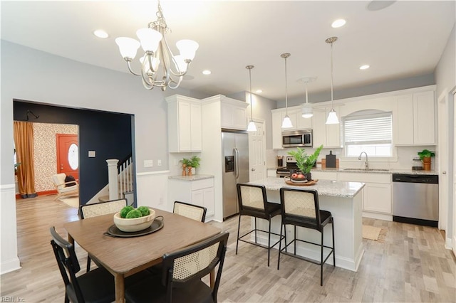 kitchen with a sink, white cabinets, a kitchen island, and stainless steel appliances