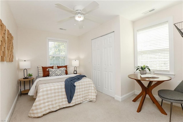 bedroom with visible vents, baseboards, a closet, and light colored carpet