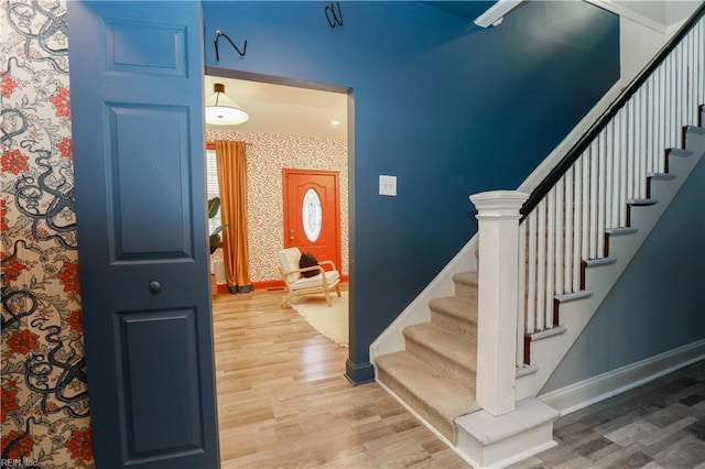 stairs featuring baseboards, wallpapered walls, and wood finished floors