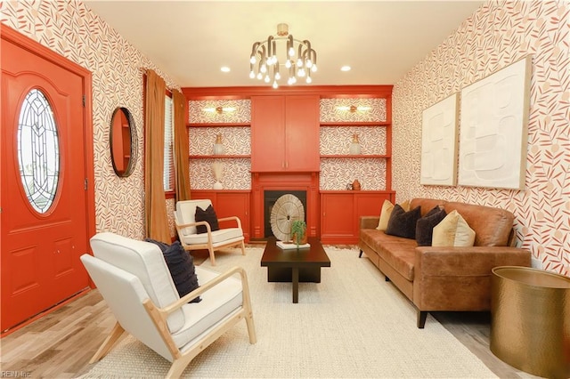 living area featuring a fireplace, a chandelier, light wood-style flooring, recessed lighting, and wallpapered walls