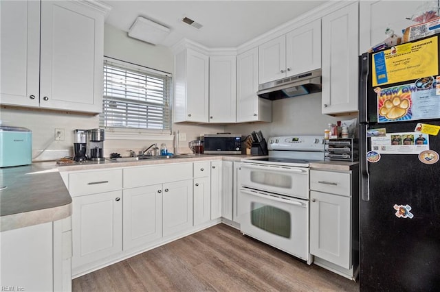 kitchen with white cabinets, freestanding refrigerator, range with two ovens, stainless steel microwave, and under cabinet range hood