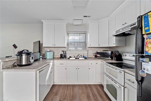 kitchen featuring white cabinets, a sink, white appliances, a peninsula, and under cabinet range hood