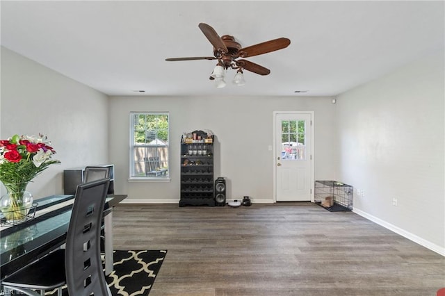 interior space with baseboards, a ceiling fan, wood finished floors, and visible vents