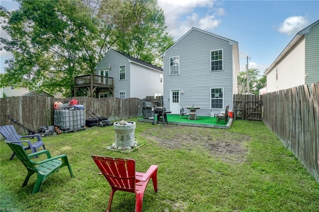 rear view of property featuring a yard, a wooden deck, and a fenced backyard