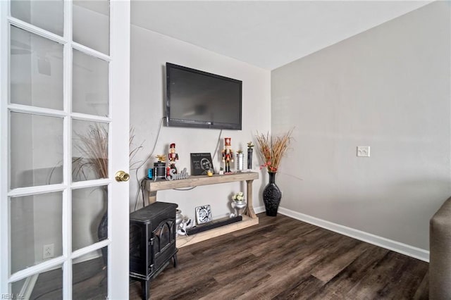 living room with baseboards, a wood stove, and dark wood finished floors