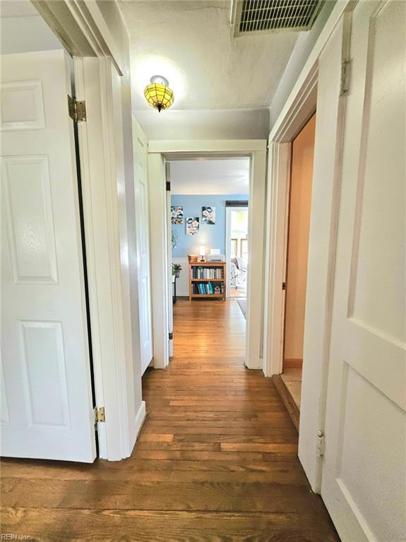 hallway with dark wood-style flooring and visible vents