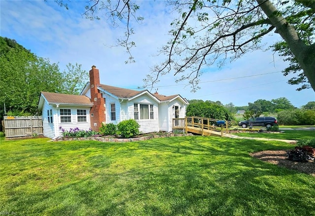 view of front of home with fence, a wooden deck, a chimney, and a front yard