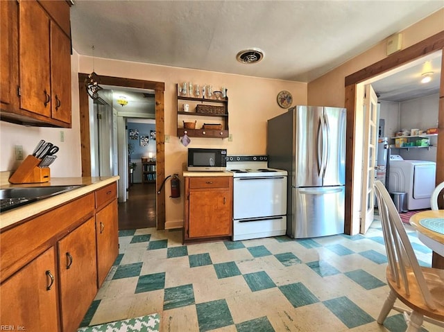 kitchen featuring brown cabinetry, independent washer and dryer, appliances with stainless steel finishes, light countertops, and light floors