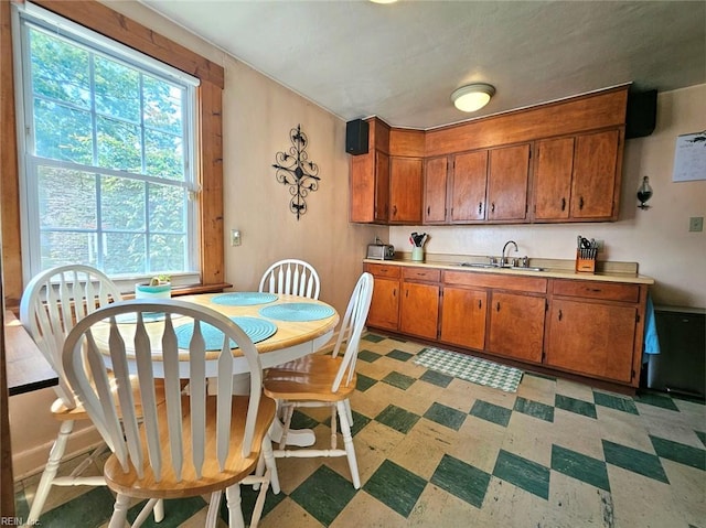 kitchen featuring a sink, light floors, brown cabinets, and light countertops