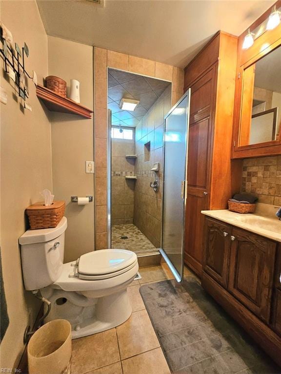 bathroom featuring tile patterned flooring, decorative backsplash, vanity, toilet, and walk in shower